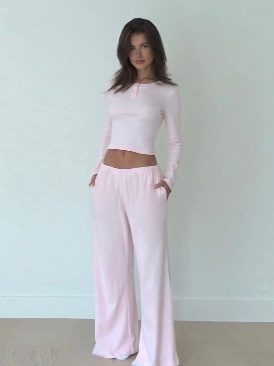 Woman wearing a light pink organic cotton long-sleeve top and organic cotton wide-leg pants against a white background